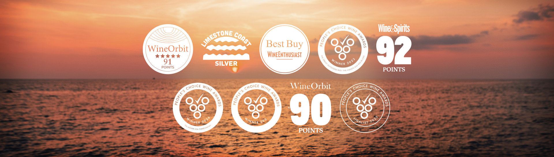 Wine award badges displayed against a sunset ocean background. Awards include 91 points from Wine Orbit, Silver from Limestone Coast, and a Best Buy from Wine Enthusiast. Also featured are a 2023 People's Choice Wine Award for The Hidden Sea Outdoors Red, a 2024 People's Choice Wine Award for The Hidden Sea Chardonnay, and 92 points from Wine & Spirits. Additional honors include a 2024 People's Choice Wine Award, 90 points from Wine Orbit, and a 2023 People's Choice Wine Awards finalist badge.